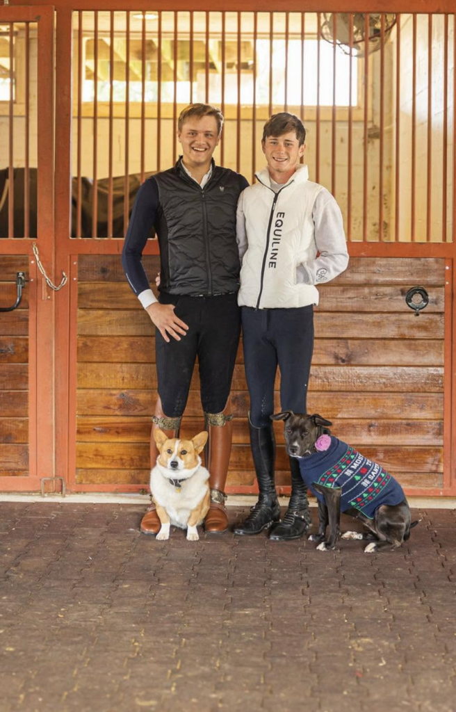 Kevin Callaway and Garrett Saylors standing in a barn aisle with their dogs